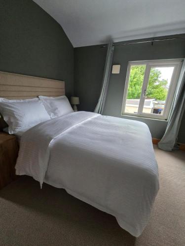a large white bed in a bedroom with a window at Cozy Town house in Athlone