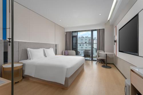 a hotel room with a white bed and a flat screen tv at Holiday Inn Express Lijiang Ancient Town by IHG in Lijiang