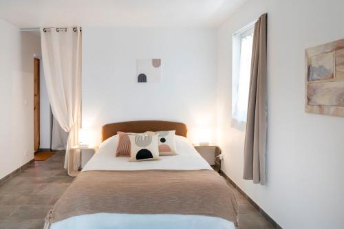 ein weißes Schlafzimmer mit einem großen Bett mit Kissen in der Unterkunft Gîte Au Milieu D'un Airial in Baudignan