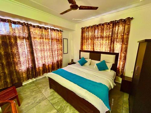 Un dormitorio con una cama grande con almohadas azules. en Hotel Om Palace Mcleodganj HP, en Dharamshala
