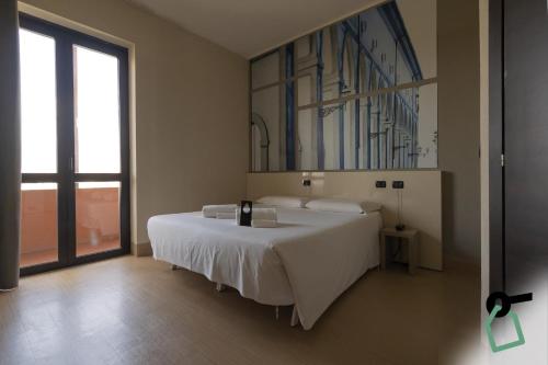 a bedroom with a large white bed with a painting on the wall at Hotiday Firenze Guidoni in Florence