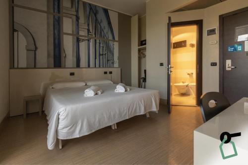 a bedroom with a white bed with towels on it at Hotiday Firenze Guidoni in Florence