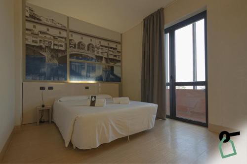 a white bed in a room with a window at Hotiday Firenze Guidoni in Florence
