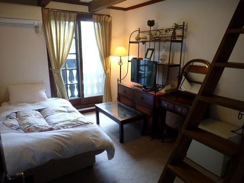 a bedroom with a bed and a dresser with a television at Pension Belnina in Hakuba