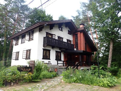 a large white house with a balcony at Pension Belnina in Hakuba