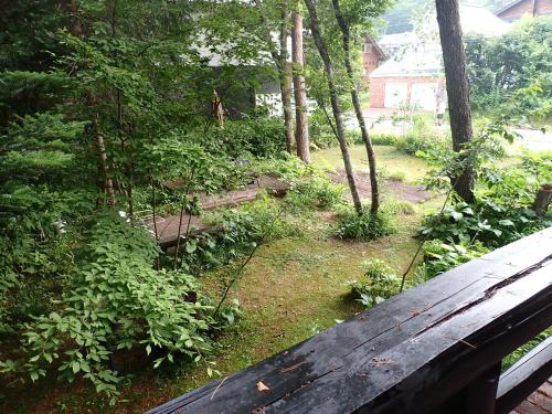 a view of a garden with a wooden bench at Pension Belnina in Hakuba