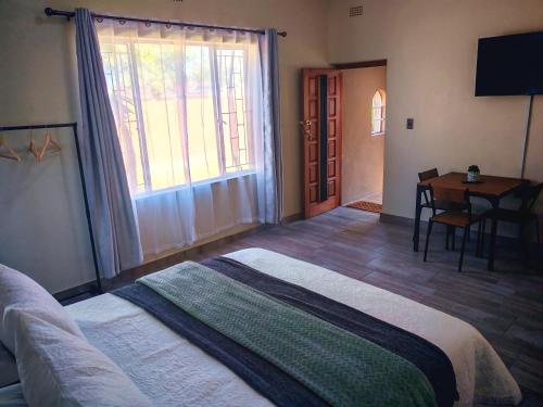 a bedroom with a bed and a table and a desk at African Hoopoe Inn in Polokwane