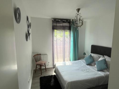 - une chambre avec un lit et une fenêtre ornée d'un lustre dans l'établissement Appartement 2 pièces terrasse Magny le Hongre, à Magny-le-Hongre