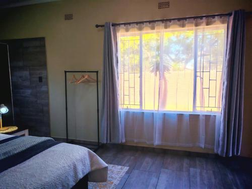 a bedroom with a large window with a palm tree at African Hoopoe Inn in Polokwane
