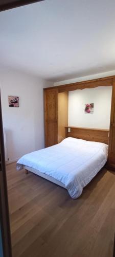 a bedroom with a white bed with a wooden headboard at Appartement T2 Vue montagne in Cauterets