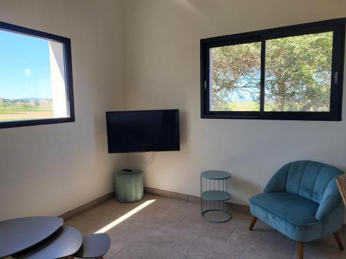 a living room with a blue chair and a flat screen tv at Domaine de l'Envolée in Tourbes