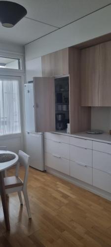 a kitchen with white cabinets and a table and a chair at Harju Rally with sauna in Jyväskylä