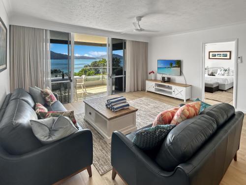 a living room with two leather couches and a television at Beach Lodges Premium in Hamilton Island