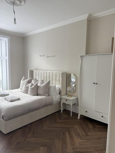 a white bedroom with a large bed and a white cabinet at Murraygate Townhouse in Dundee