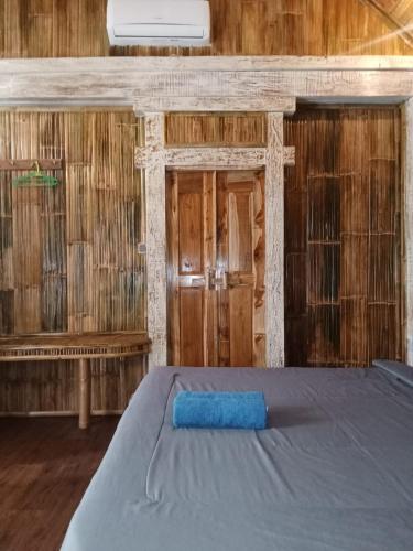 a room with a bed and a wooden wall at Kushak bungalow Gili Trawangan in Gili Trawangan