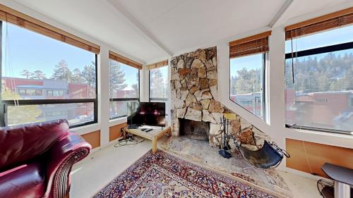 a living room with a stone fireplace and windows at Upgraded 2 Bedroom Condo with Pool in Mammoth Lakes