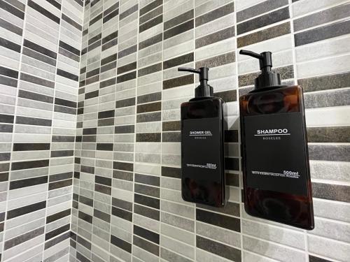 a bathroom with two soap dispensers on a tiled wall at L'icône du cinéma - Studio cosy - Gare - Centre-ville Evreux - Wifi in Évreux