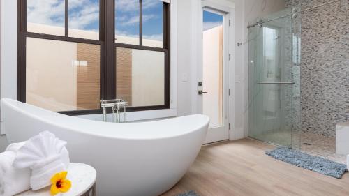a white bathroom with a tub and a shower at HOKU LANI HOUSE Heated Private Pool Spa Intro Pricing 25% off in Waimea