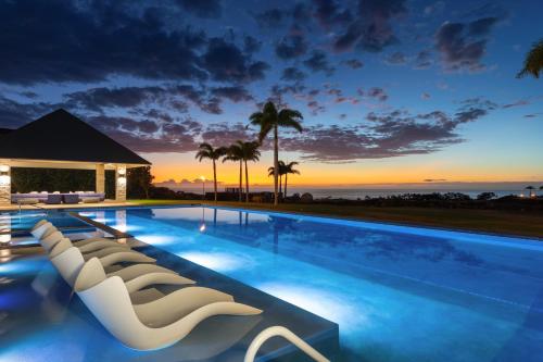 a swimming pool with chairs and a sunset at HOKU LANI HOUSE Heated Private Pool Spa Intro Pricing 25% off in Waimea