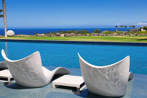two white chairs sitting next to a swimming pool at HOKU LANI HOUSE Heated Private Pool Spa Intro Pricing 25% off in Waimea