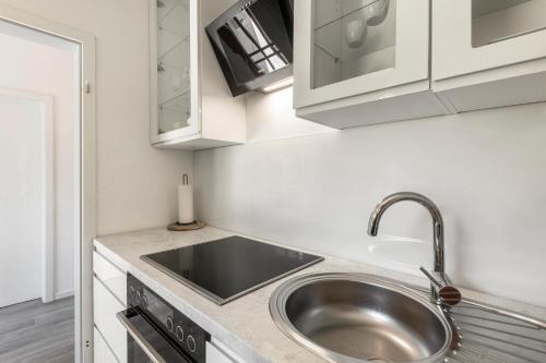 a kitchen with a sink and white cabinets at db staycation ferienpark in Niedenstein