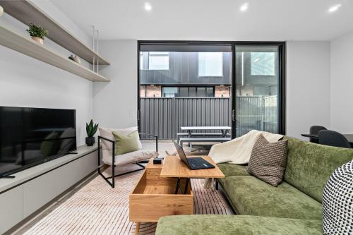 a living room with a green couch and a television at Modern 3BR Townhouse Near Adelaide CBD Workspace & Parking in Bowden