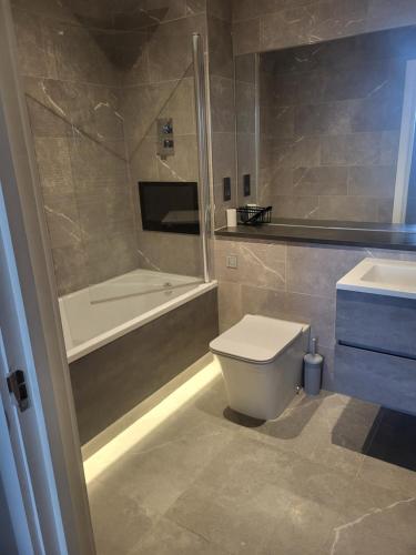 a bathroom with a tub and a toilet and a sink at The Ramsgate Bay Apartment in Ramsgate