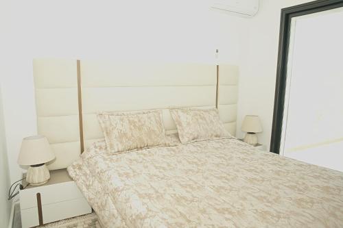 a white bedroom with a large bed with two lamps at Villa Yasmin in Temlale
