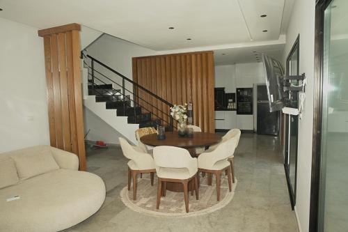 a dining room with a table and chairs and a staircase at Villa Yasmin in Temlale