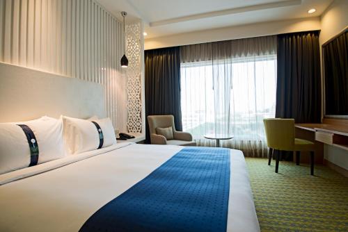 a hotel room with a large bed and a desk at Holiday Inn Amritsar Ranjit Avenue by IHG in Amritsar
