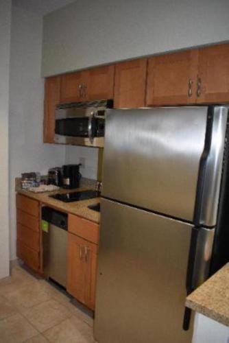 a kitchen with a stainless steel refrigerator and wooden cabinets at Studio 6 Carlsbad CA in Carlsbad