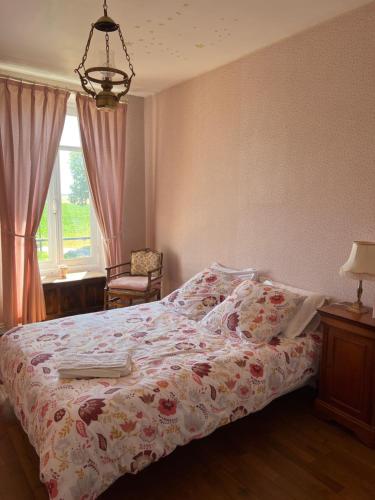 a bedroom with a bed with a flowered blanket and a window at Le Chalet in Coulmier-le-Sec
