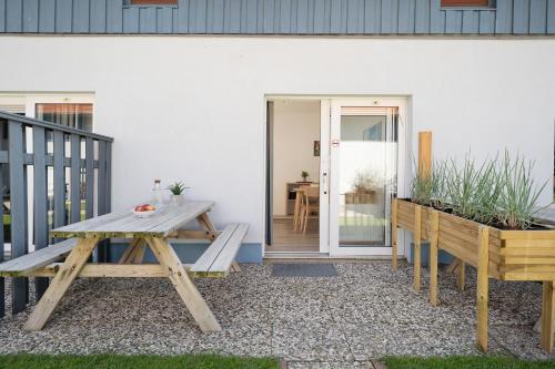 a patio with a wooden table and benches on a house at Gästehaus Sulsdorf Wohnung 18 in Sulsdorf auf Fehmarn