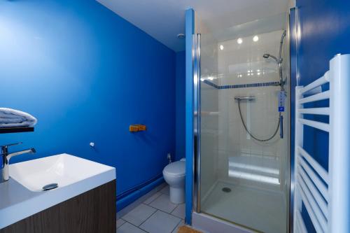 La salle de bains bleue est pourvue d'une douche et de toilettes. dans l'établissement Gite Triskel, à Cast