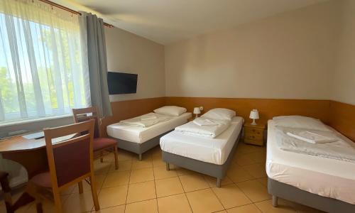 pokój z trzema łóżkami, stołem i biurkiem w obiekcie City Hostel w Szczecinie