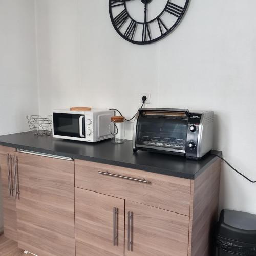 un comptoir avec un micro-ondes, un four grille-pain et une horloge dans l'établissement Le sourire de Mona Lisa 2 étoiles 100m du château, à Amboise