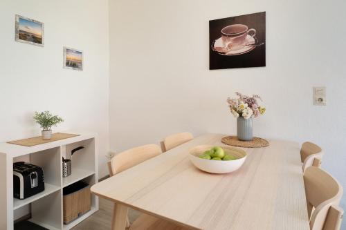 a dining room table with a bowl of apples on it at Gästehaus Sulsdorf Wohnung 16 in Sulsdorf auf Fehmarn