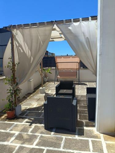 a patio with white curtains and chairs on a roof at Vimar in San Vito dei Normanni
