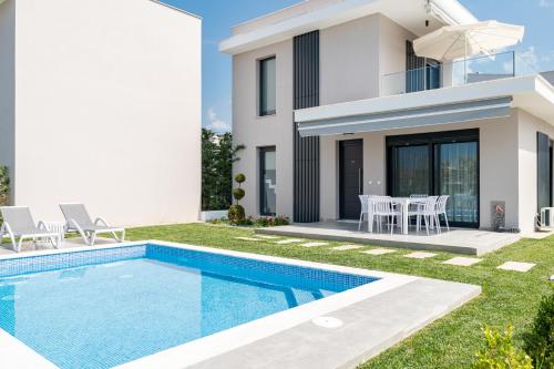a villa with a swimming pool in front of a house at Nefeli & Nefeli Luxury Residential Complexes in Ofrínion