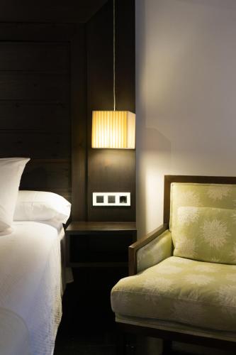 a bedroom with a bed and a chair and a lamp at La Plaza in Hervás