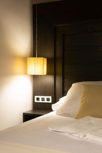 a bedroom with a white bed with a black headboard at La Plaza in Hervás