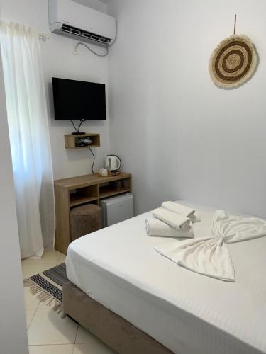 ein weißes Schlafzimmer mit einem Bett und einem Fernseher in der Unterkunft Helios Rooms in Sarandë