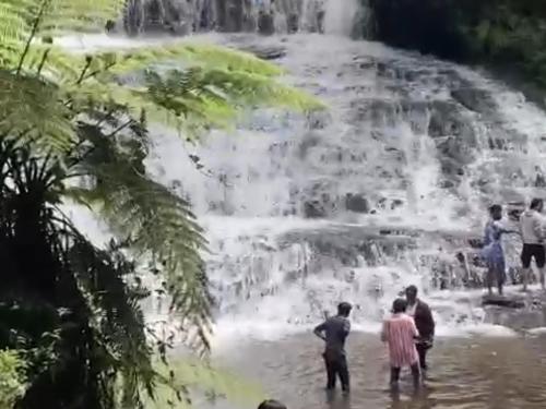 a group of people standing in front of a waterfall at Akshay INN in Kodaikānāl