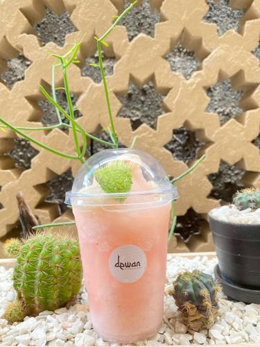 a drink in a plastic cup sitting next to a cactus at Dewan Bangkok in Bangkok