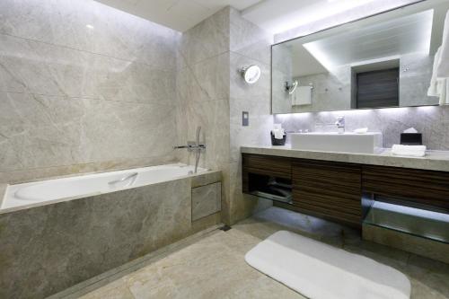 a bathroom with a tub and a sink and a bath tub at New World Millennium Hong Kong Hotel in Hong Kong