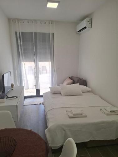 a white room with two beds and a television at Zen Studio Apartman in Kotor