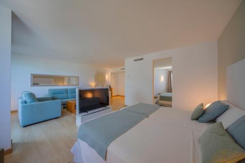 a bedroom with a large white bed and a blue couch at Playa Esperanza Resort Affiliated by Meliá in Playa de Muro