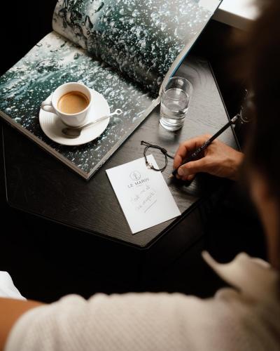 a person sitting at a table with a cup of coffee at Le Marin Hotel Rotterdam City - Handwritten Collection in Rotterdam