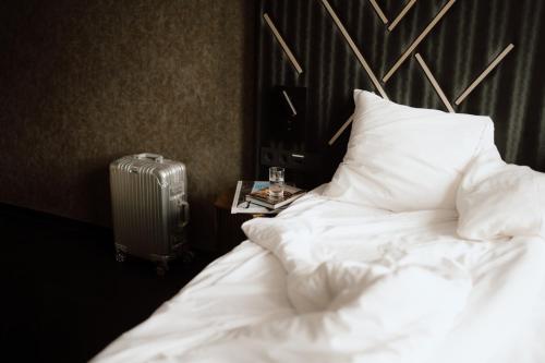a bedroom with a white bed and a suitcase at Le Marin Hotel Rotterdam City - Handwritten Collection in Rotterdam