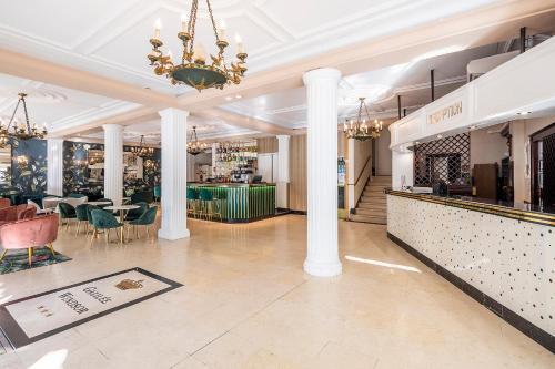 ルルドにあるHôtel Galilée Windsorの柱とテーブル、シャンデリアのあるロビー